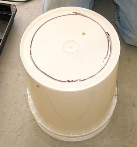White bucket turned upside down , with a large circle drawn on its bottom.
