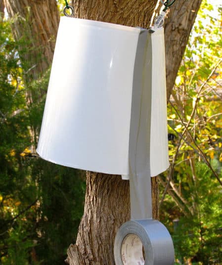  Seau blanc suspendu avec des fils et autour d'un tronc d'arbre.