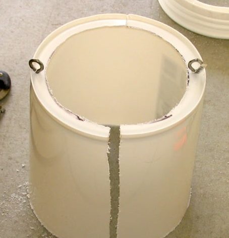 White bucket setting bottom up with an eyebolt on each side.