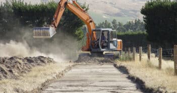 Photo of bulldozer tearing up grassland to make a road.
