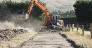 Photo of bulldozer tearing up grassland to make a road.